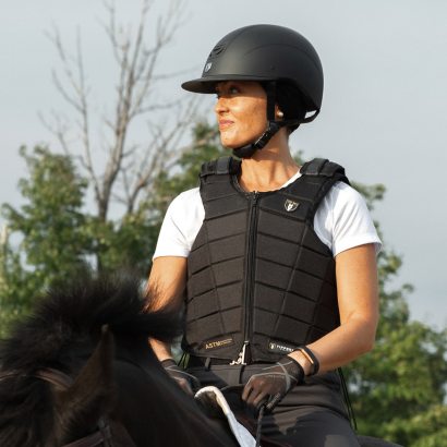 A rider wearing a safety vest on horseback.