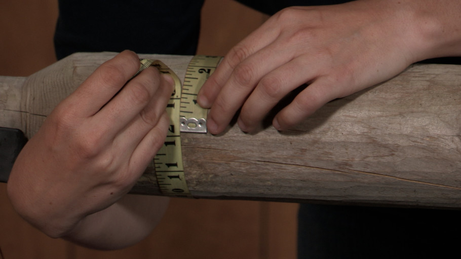 A person measuring the circumference of a ground pole.