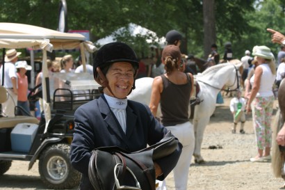 An older rider smiling at a horse show.