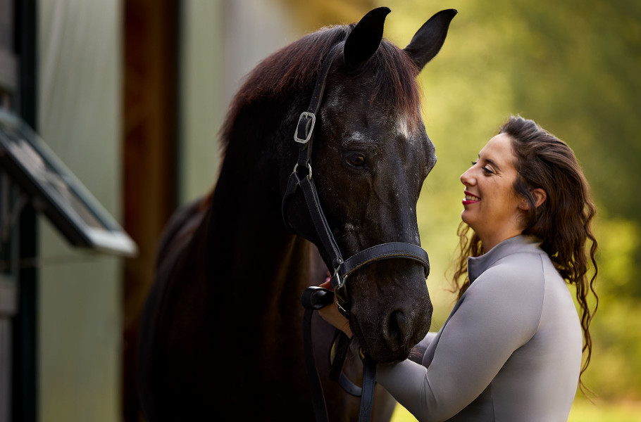 An owner smiling at her black senior horse.