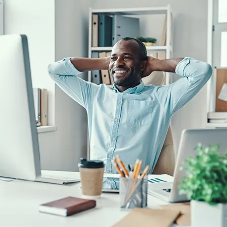 Man sitting relaxed at computer with hands behind his head