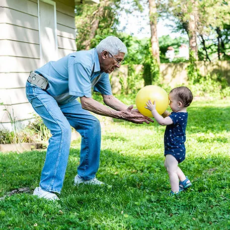 An elderly man and an infant outside, he bends down without back pain