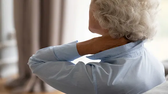 Older woman holding her neck in discomfort