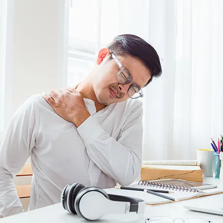 Man streching his neck at a computer desk