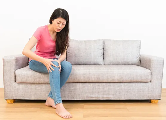 Woman on sofa holding her knee