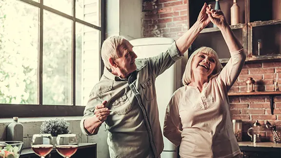 Older man and women smiling and dancing in kitchen
