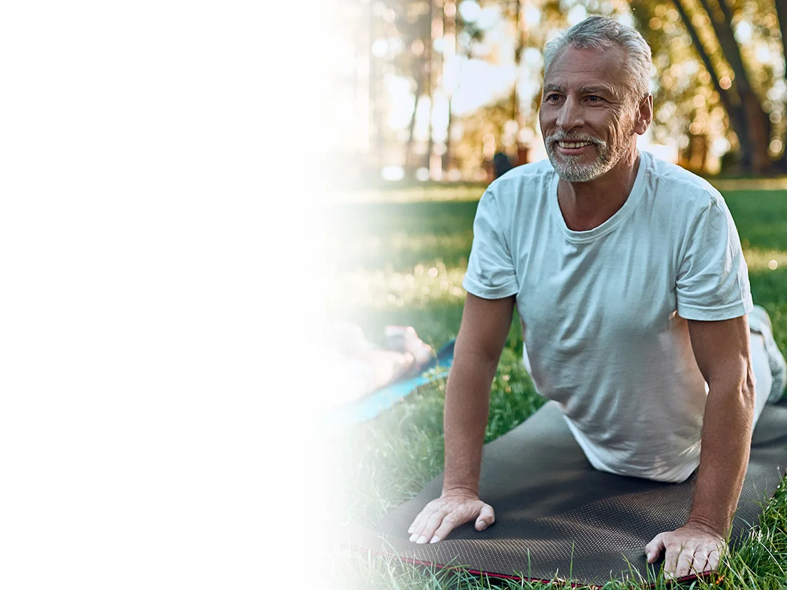 an elderly couple on yoga mats outside stretching their backs