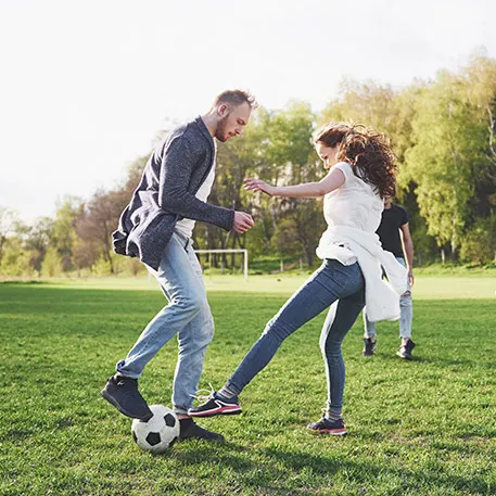 Friends playing football on open field on a sunny