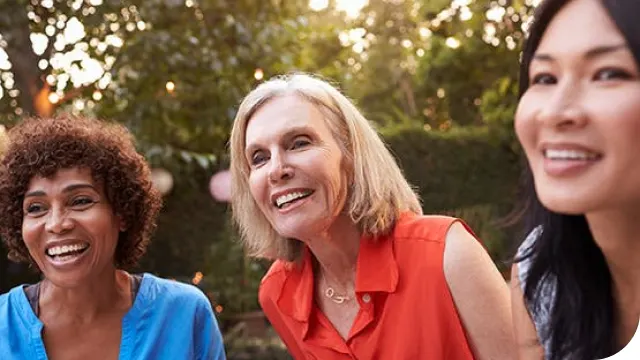 three women smiling outside