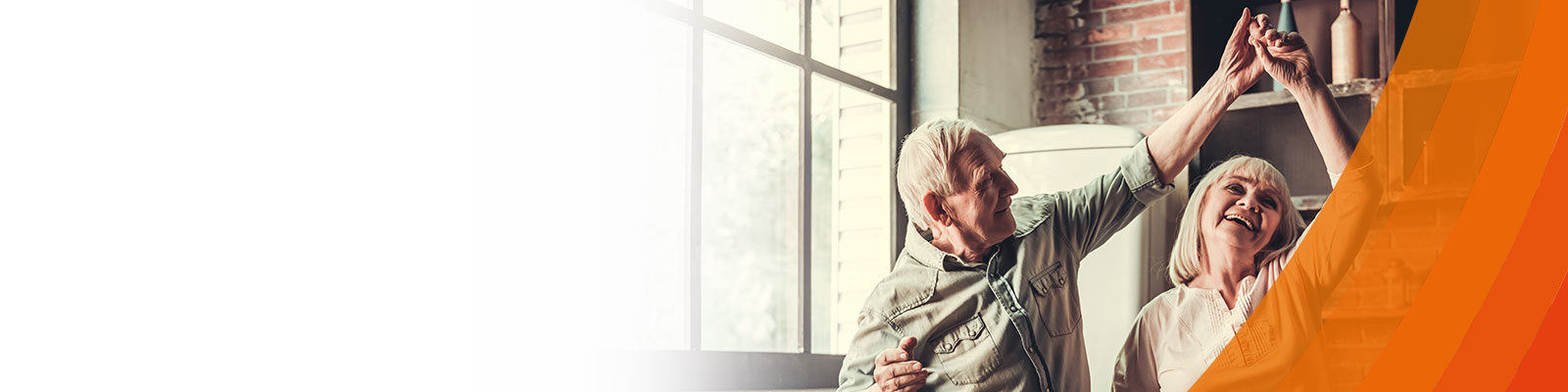  Older man and women smiling and dancing in kitchen with orange voltaren colours 