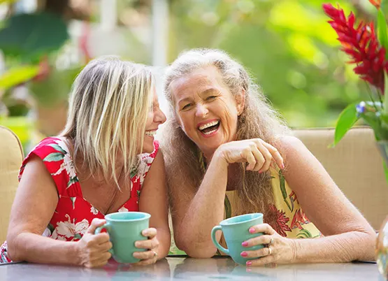 middle aged women sitting at table and laughing