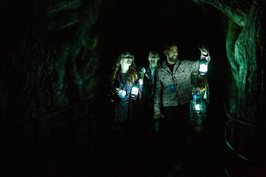 A group walking through the Forbidden Forest at the Studio Tour - they are holding lanterns.