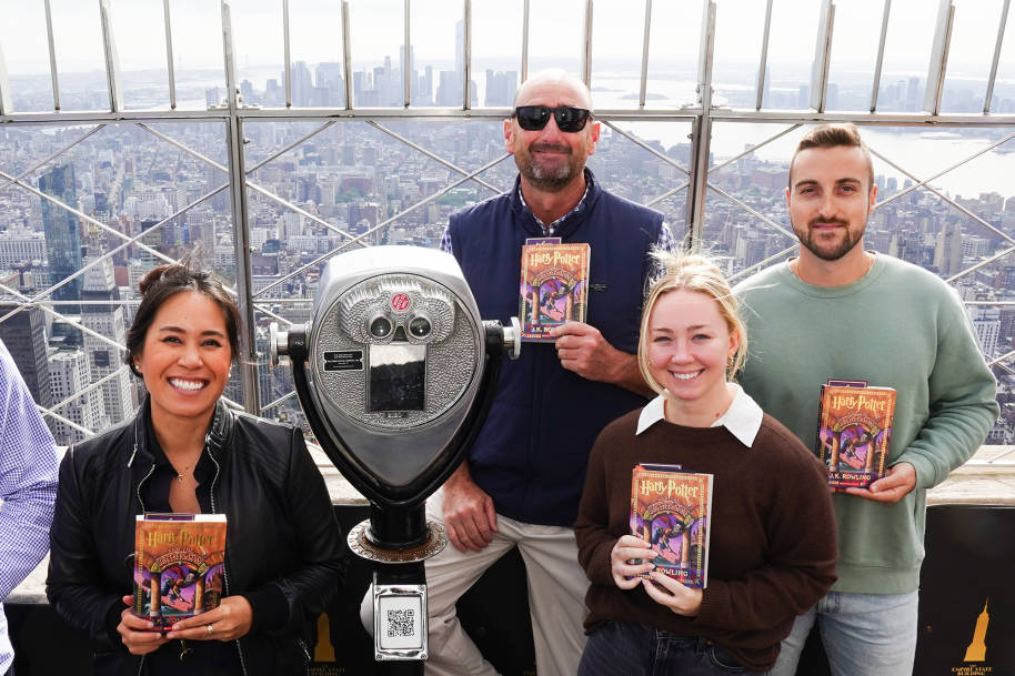 People gathered on the observation deck of the Empire State Building holding copies of Sorcerer's Stone