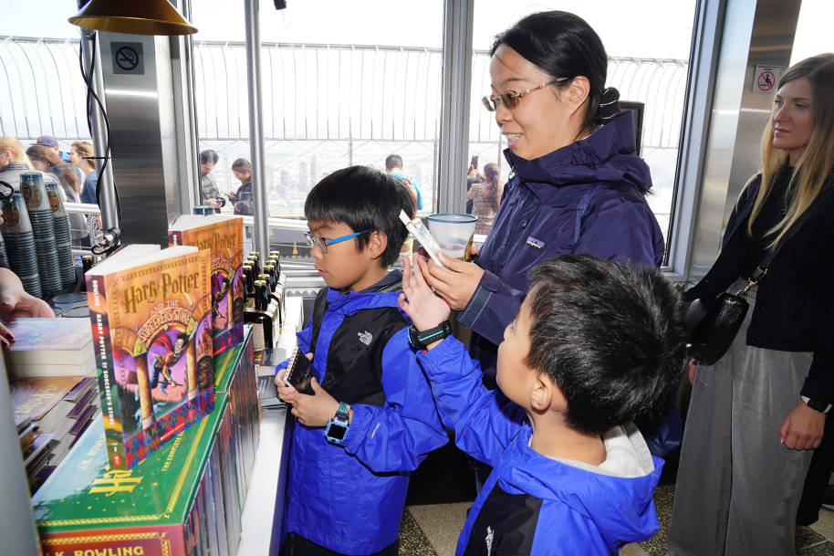 Two boys and a woman look at the copies of Sorcerer's Stone on the pop-up cart.