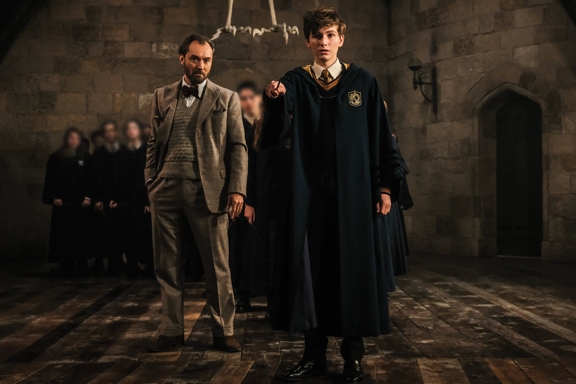 Albus Dumbledore and young Newt Scamander in a lesson. Newt has his wand raised as Dumbledore watches.