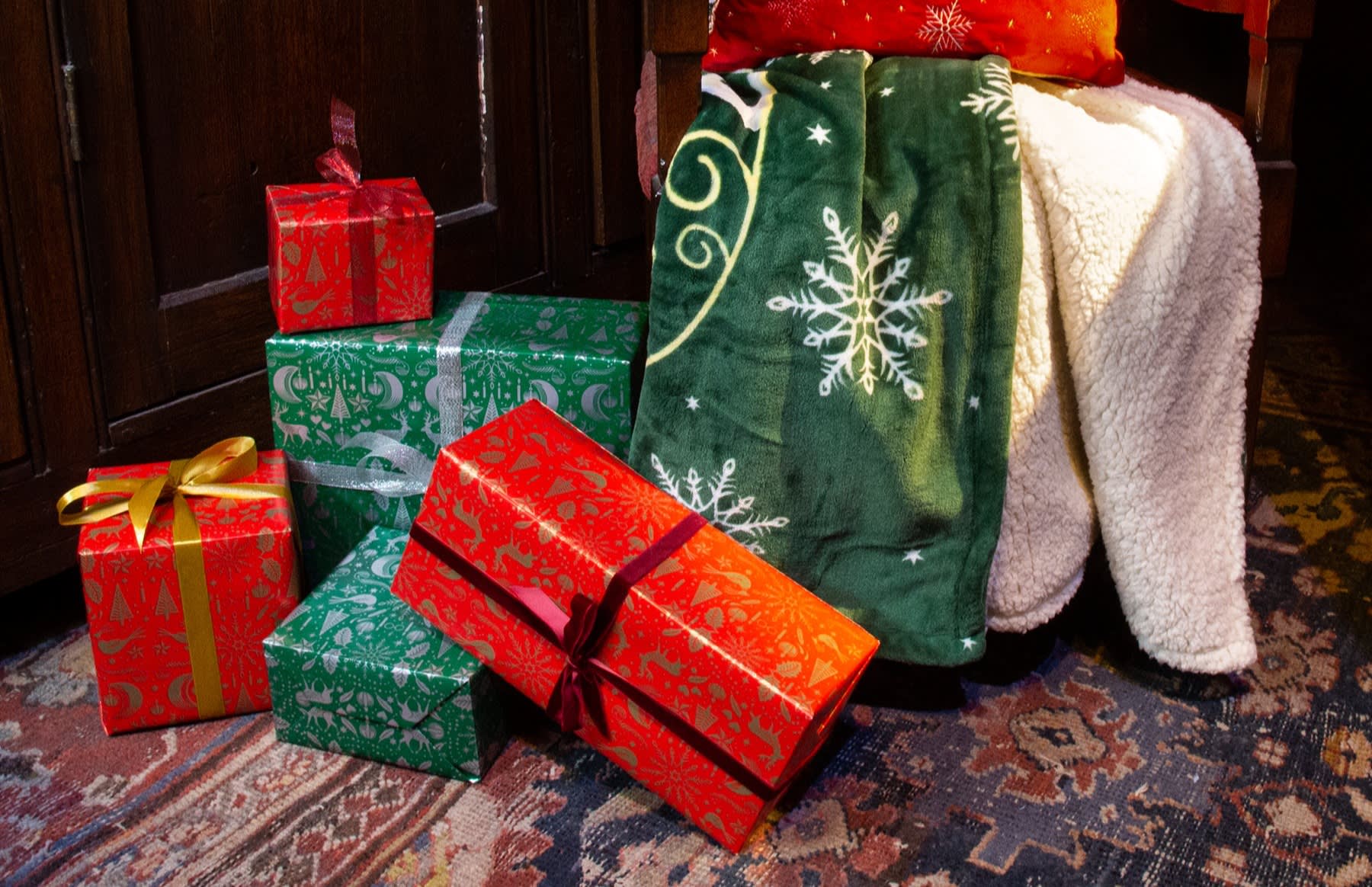A festive picture of a wizarding world-themed throw on a chair with some cushions and presents