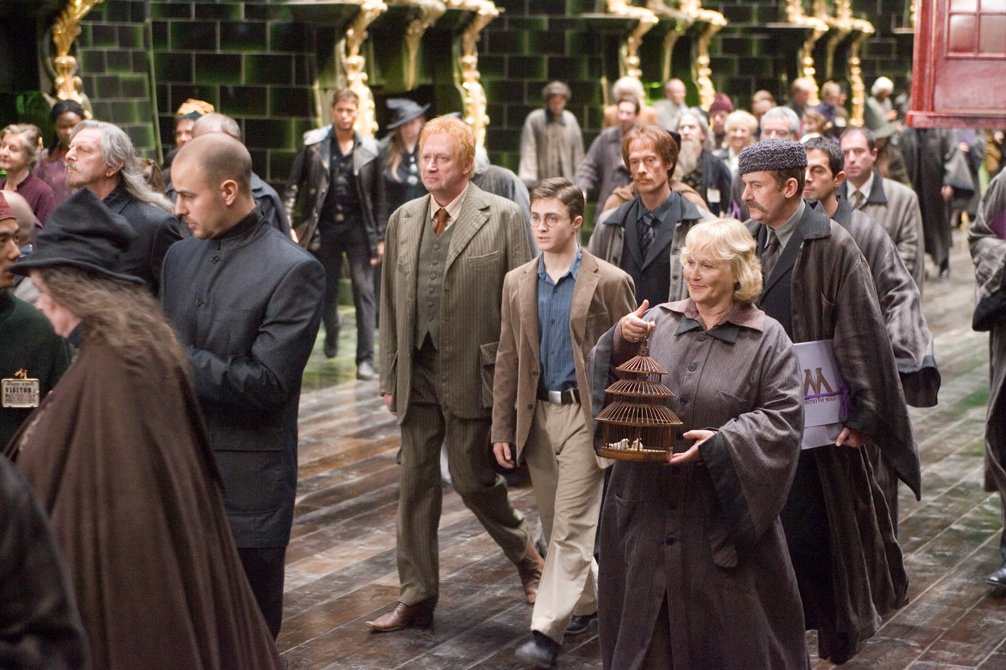 Harry Potter and Arthur Weasley are walking through the crowded atrium at the Ministry of Magic