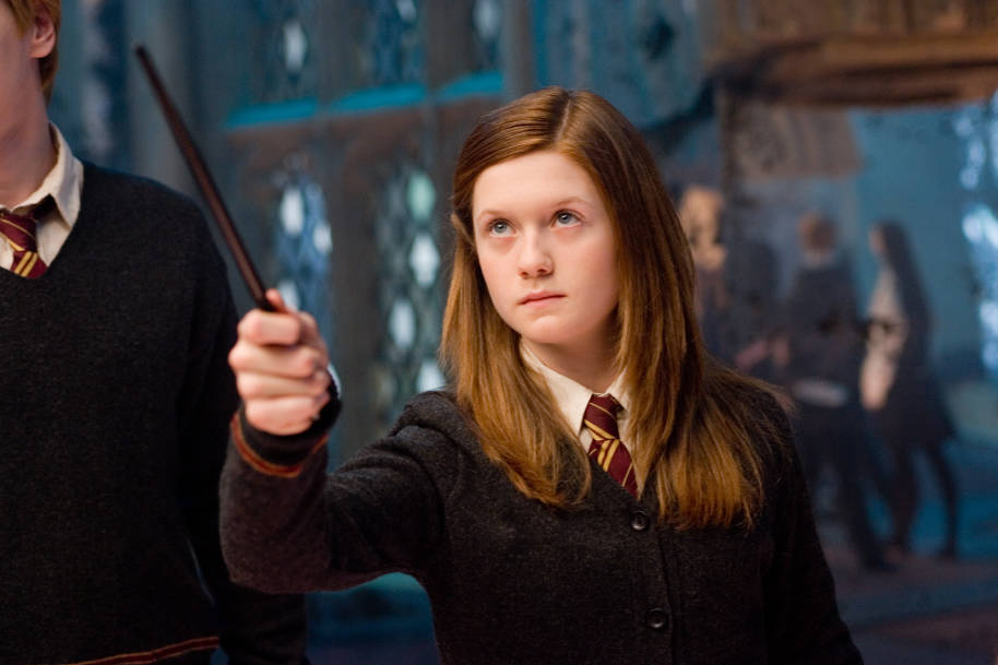 Ginny Weasley in the Room of Requirement holding up her wand and looking determined.