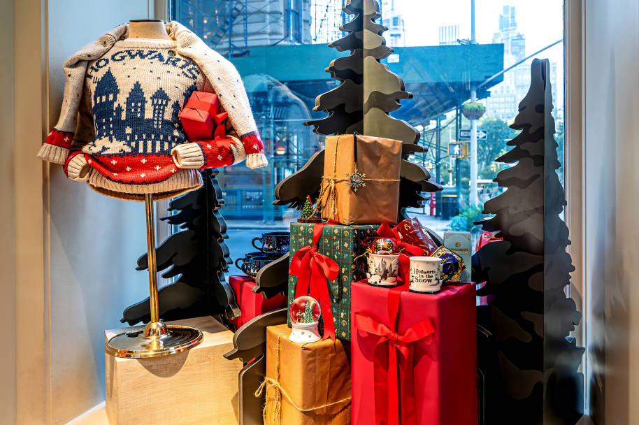The inside of the Harry Potter New York window display with a mannequin wearing Christmas jumper and a pile of presents.