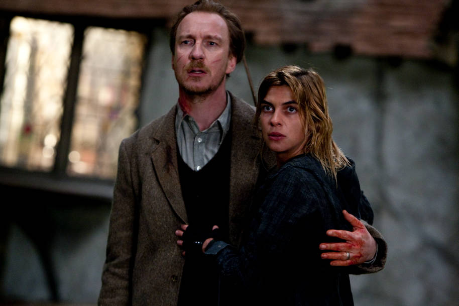 Lupin and Tonks standing outside The Burrow. Lupin has his arm around Tonks and they both look concerned.