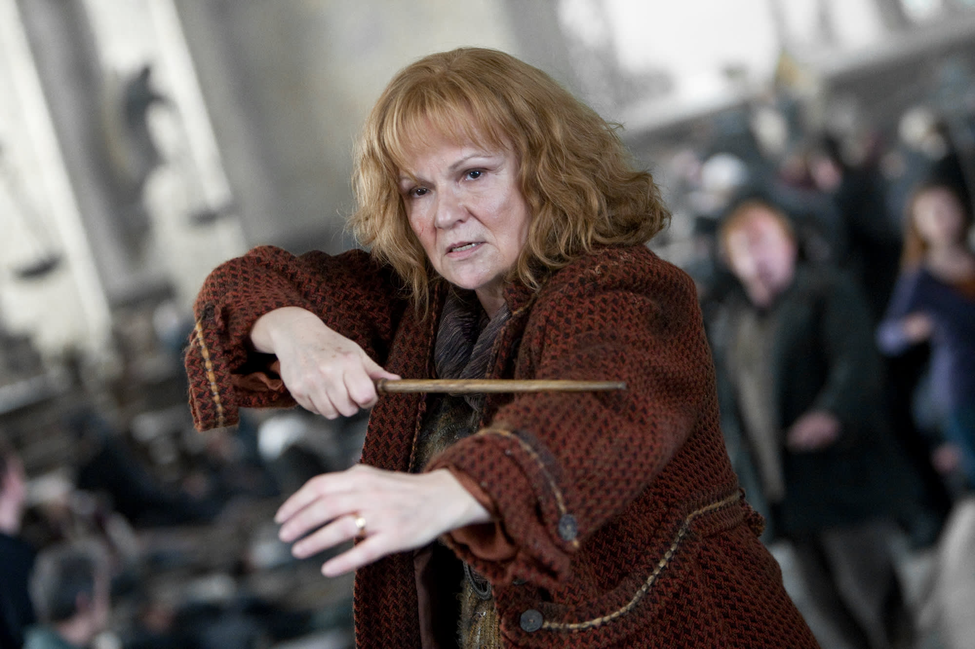 A close-up of Molly Weasley looking determined and holding her wand up while duelling in the Great Hall at the Battle of Hogwarts
