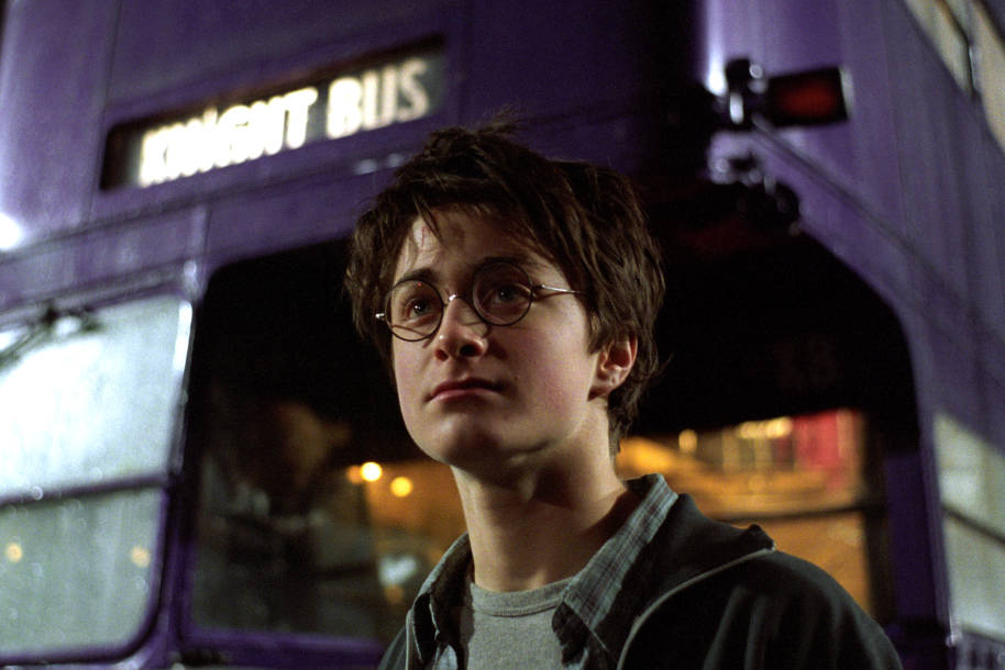 Harry Potter standing outside the purple Knight Bus in London.
