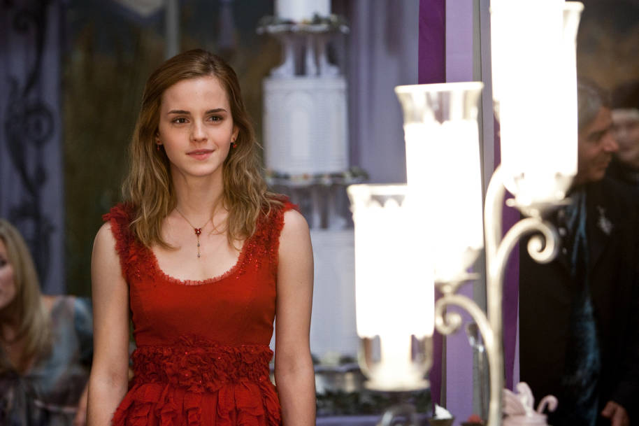 Hermione wearing a red dress and smiling at Bill and Fleur's wedding.