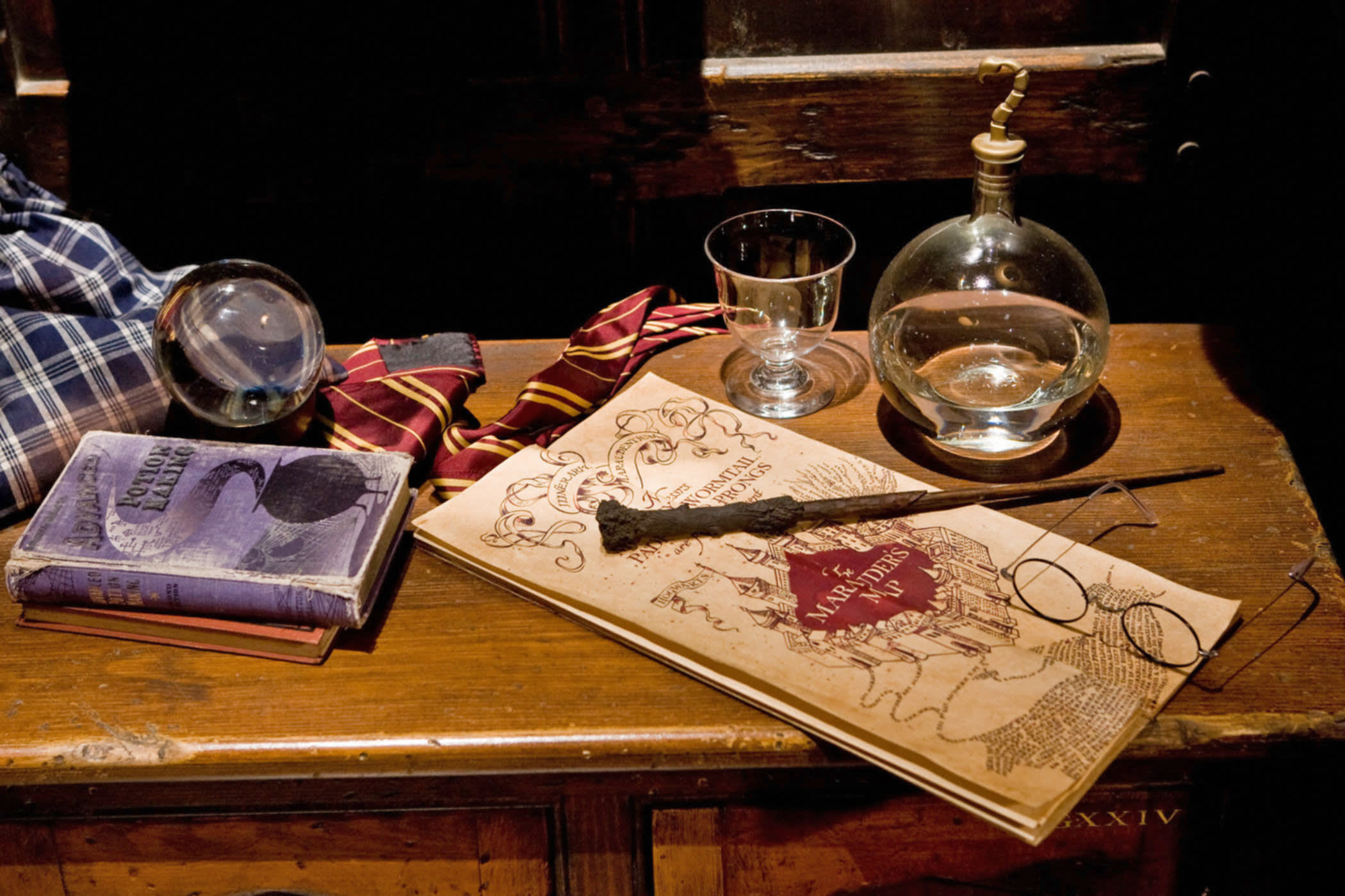 Harry's wand and glasses resting on the Marauders map on a desk 