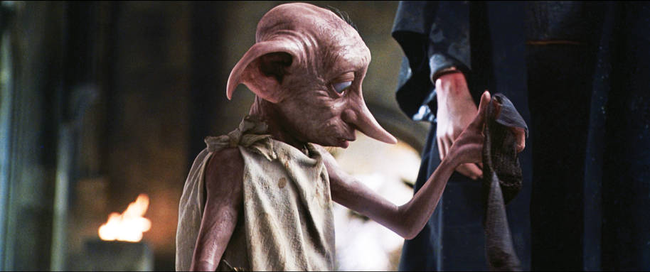 Dobby is holding a sock in his hand and looking at it.