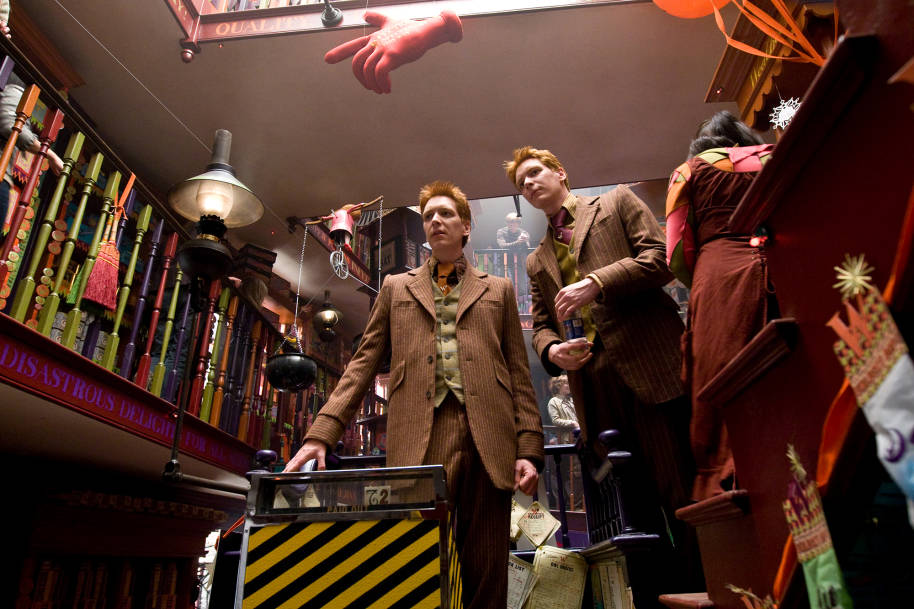 Fred and George wearing suits and standing together in Weasleys' Wizard Wheezes.
