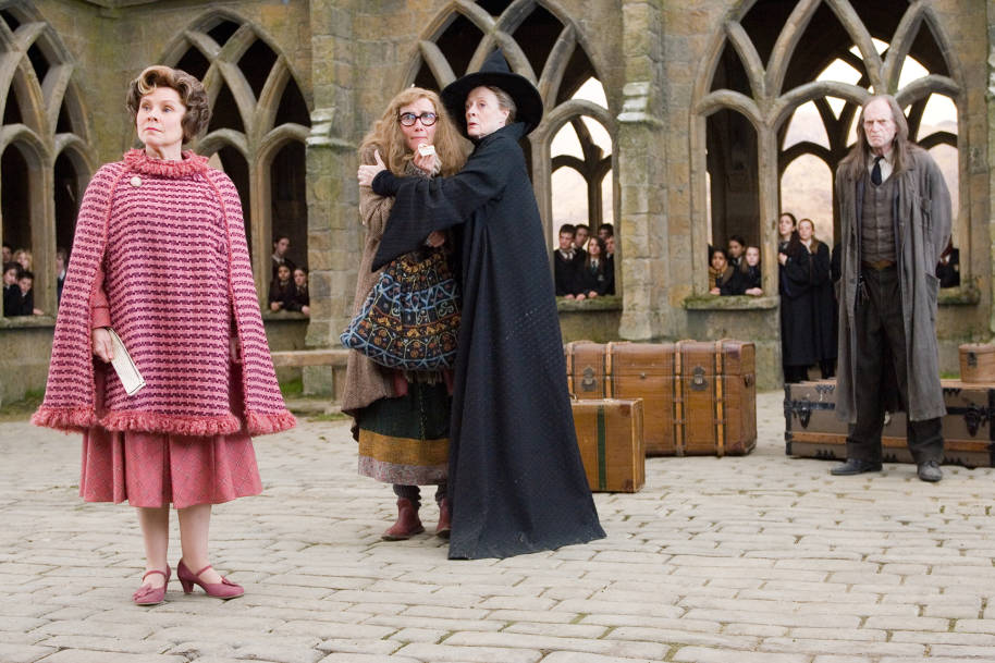 Professor Trelawney is standing in the courtyard upset after being sacked while Professor McGonagall comforts her. Professor Umbridge and Argus Filch are stood there too