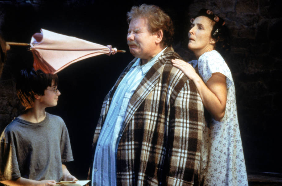 Hagrid pointing his pink umbrella at Vernon and Petunia Dursley while Harry looks on.