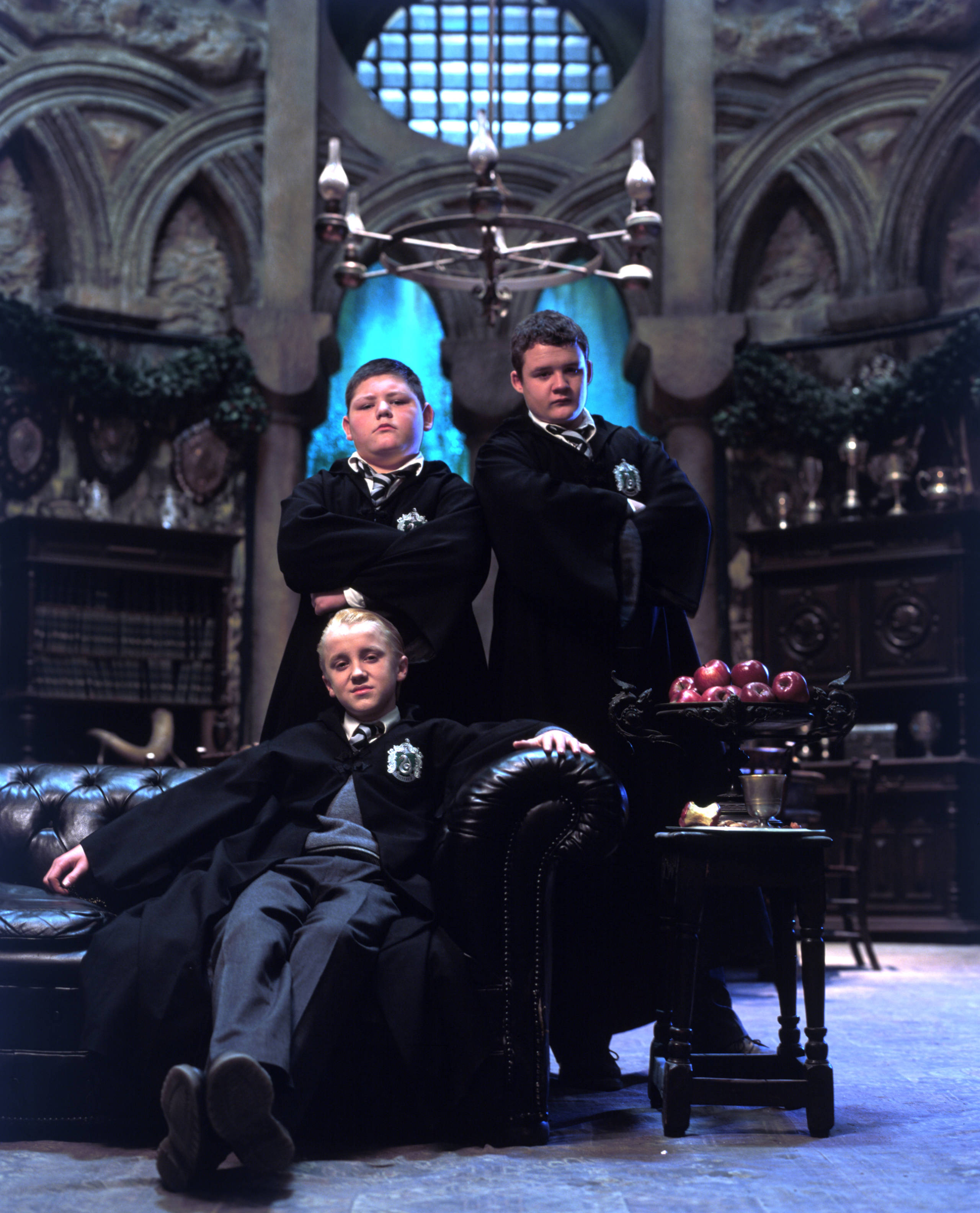 Draco lounges in front of Crabbe and Goyle in Slytherin common room.