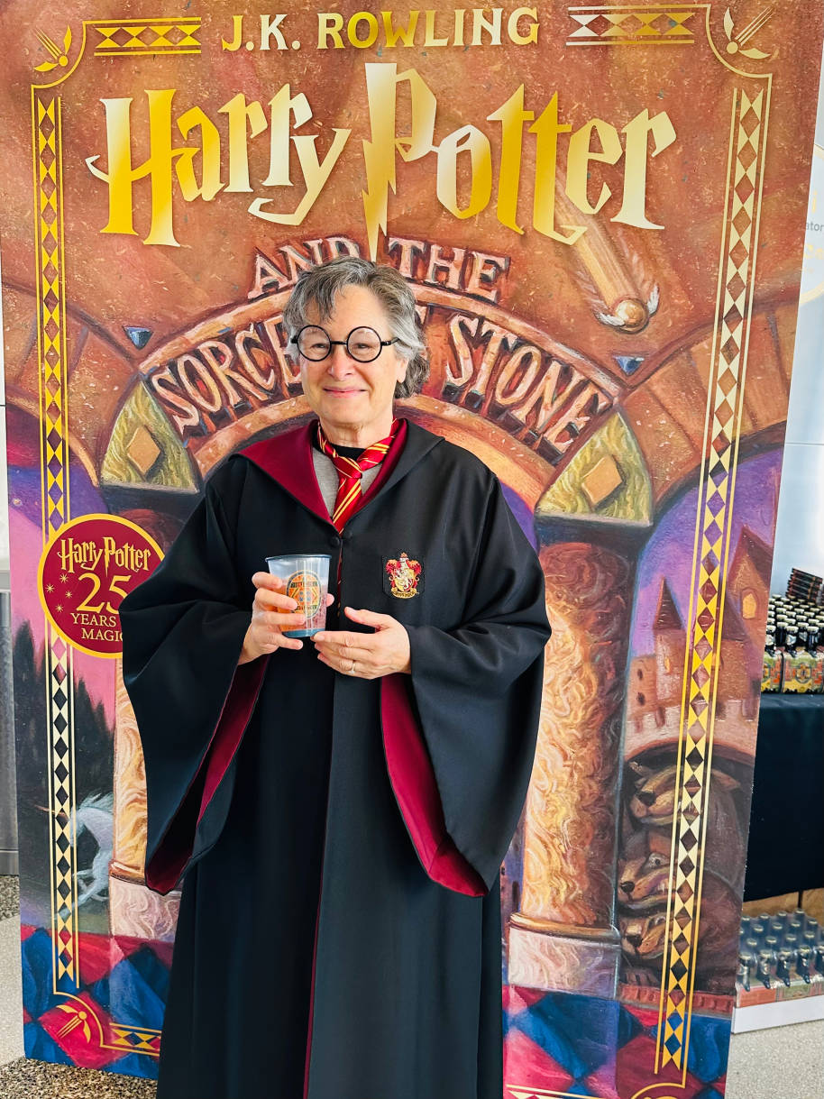 A woman wearing Gryffindor robes and holding a Butterbeer
