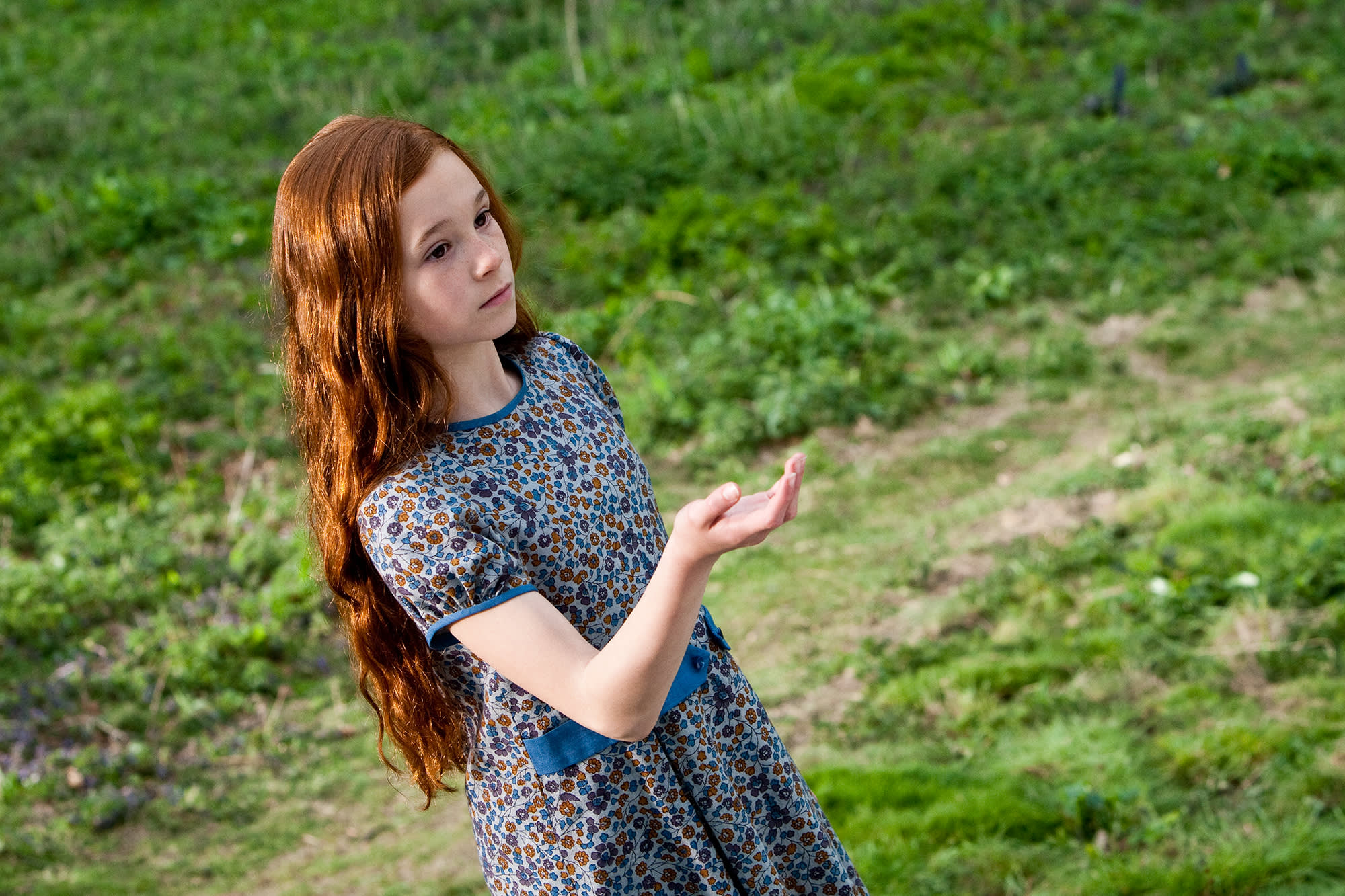 A young Lily standing on the grass with her hand outstretched  