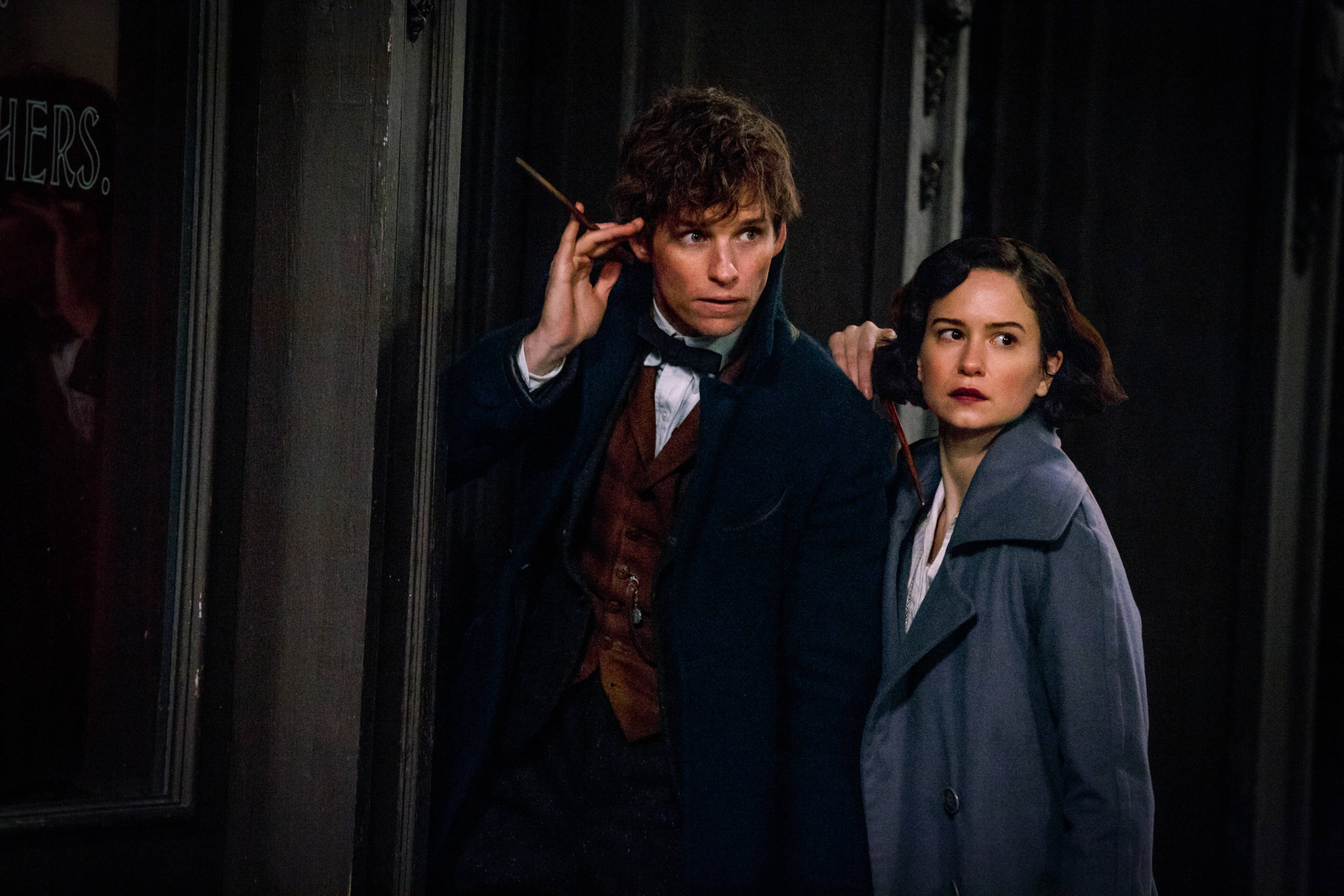 Newt Scamander and Tina Goldstein, played by Eddie Redmayne and Katherine Waterston, stand with their wands raised for action