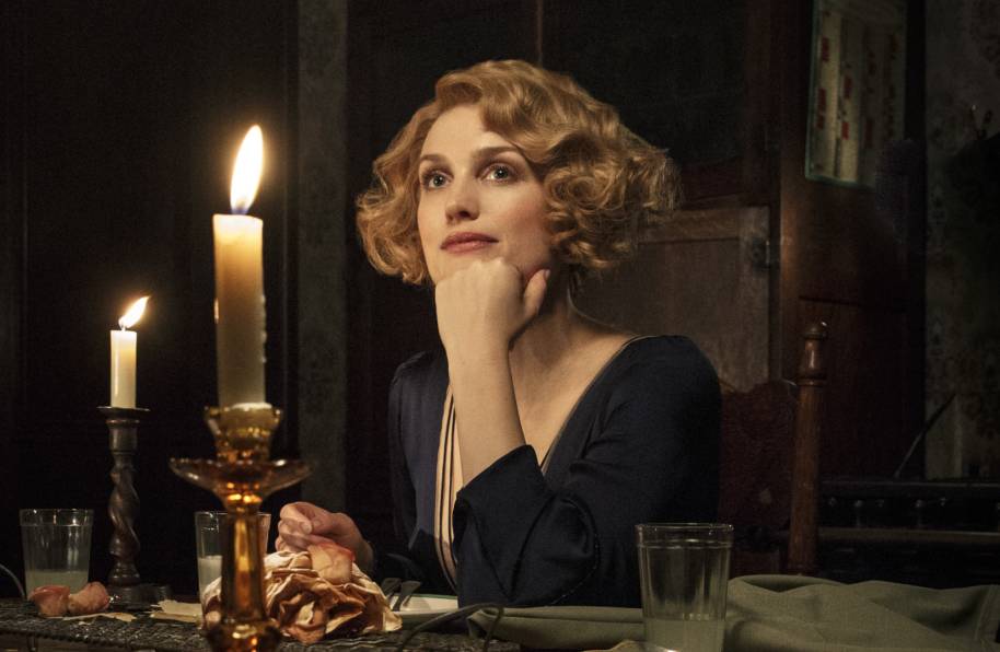 Queenie Goldstien rests her chin on her hand as she sits at a candlelit dinner table 