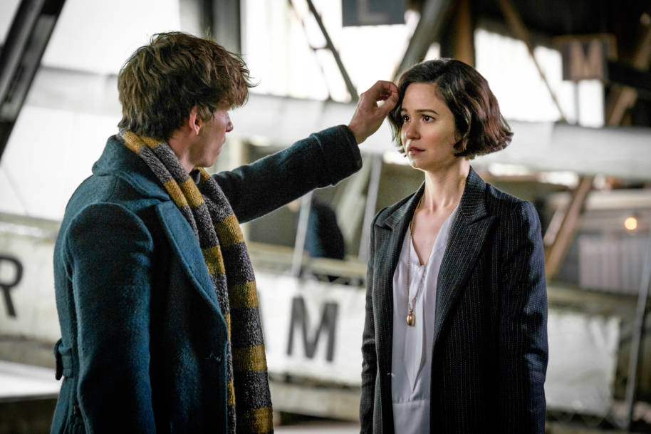 Newt Scamander tucks Tina Goldstein's hair behind her ear in a tender moment at the port