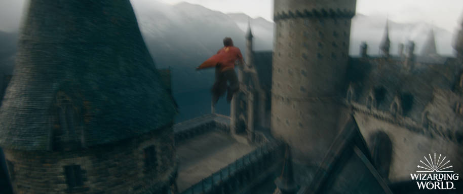 A person in Gryffindor Quidditch robes flying over Hogwarts