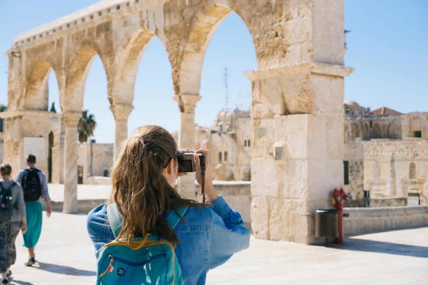 woman with backpack taking photo while abroad in europe
