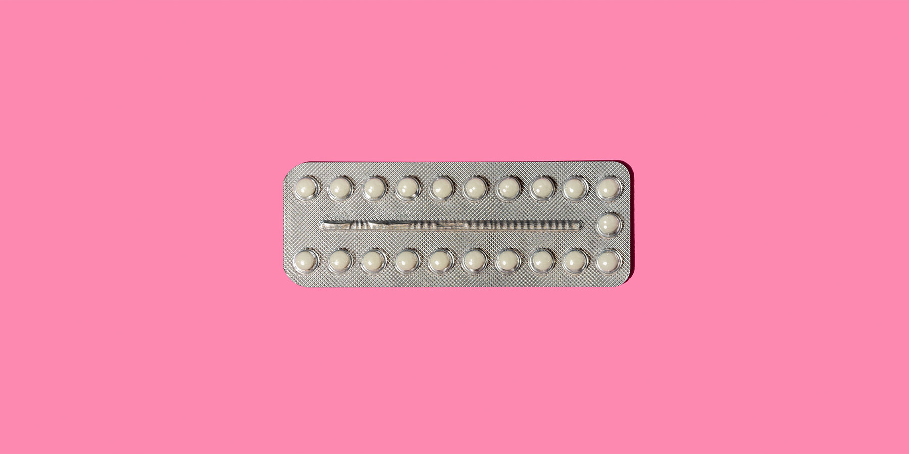 Pack of progesterone pills against a pink background