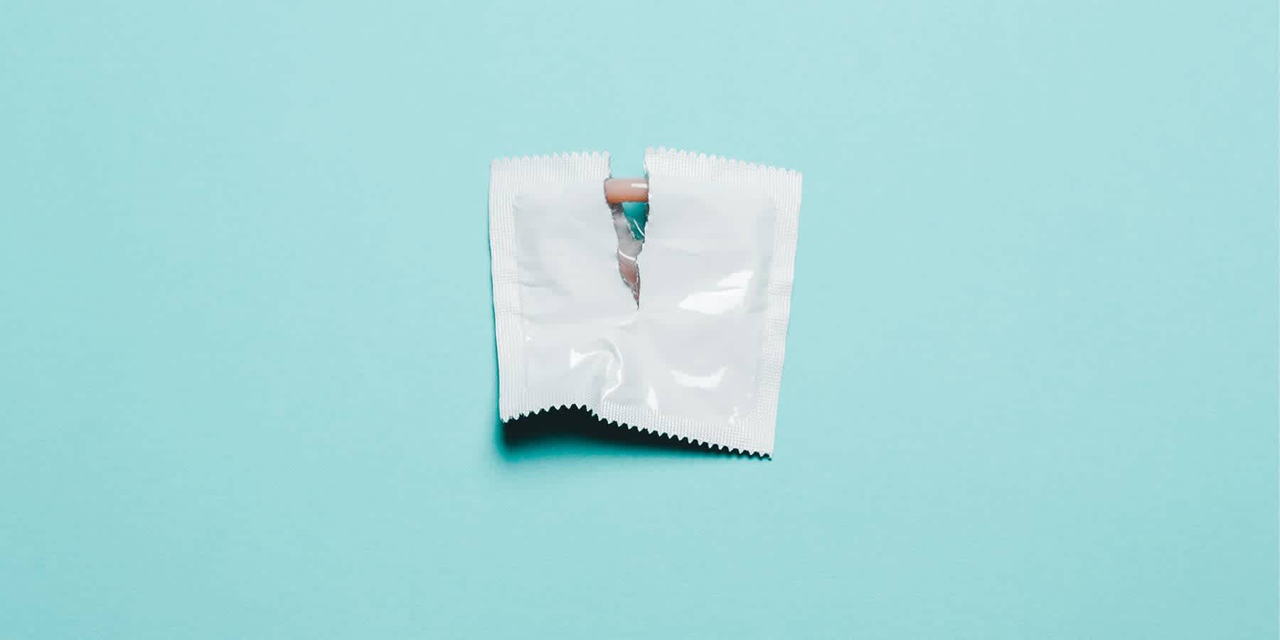 Opened condom packet against light blue background to represent condom usage to prevent STD transmission through oral sex