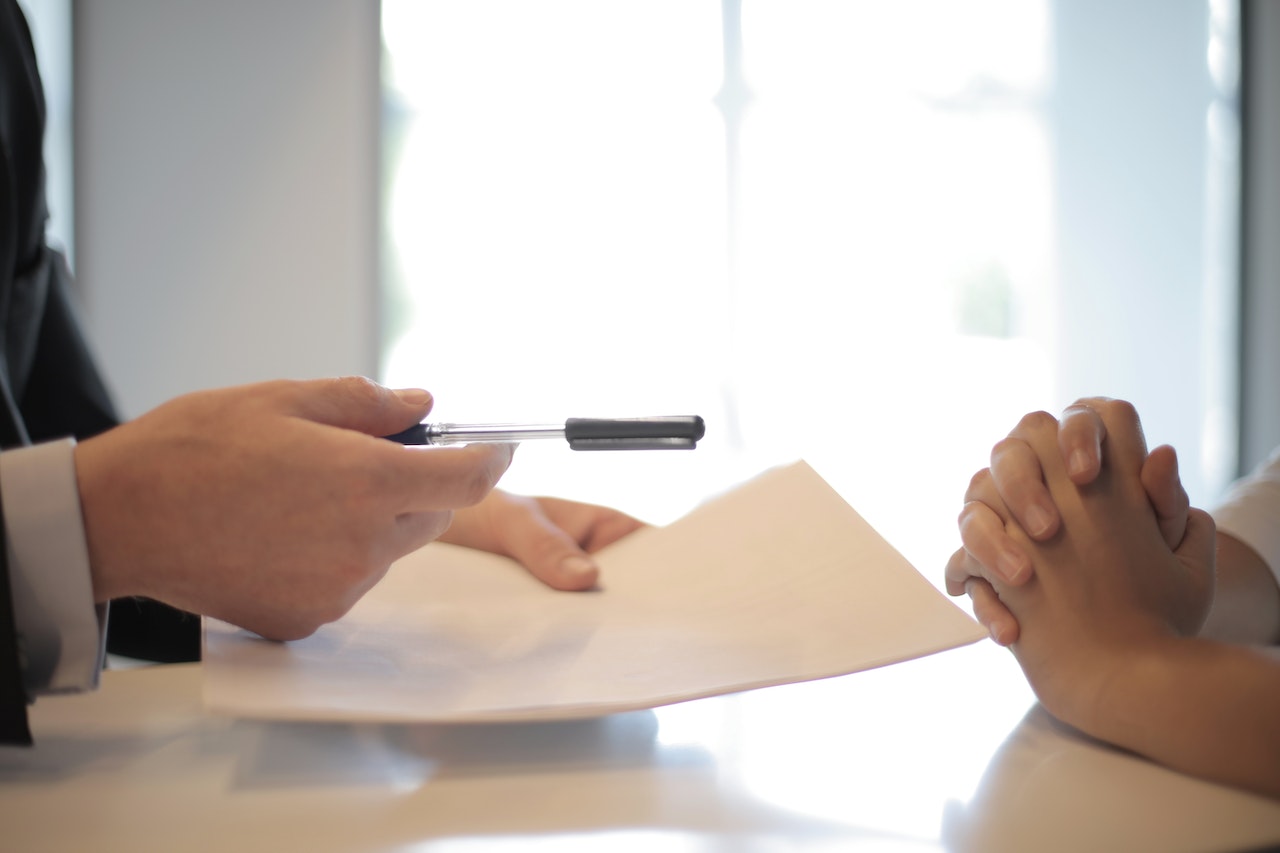 Person handing insurance coverage document for other person to sign