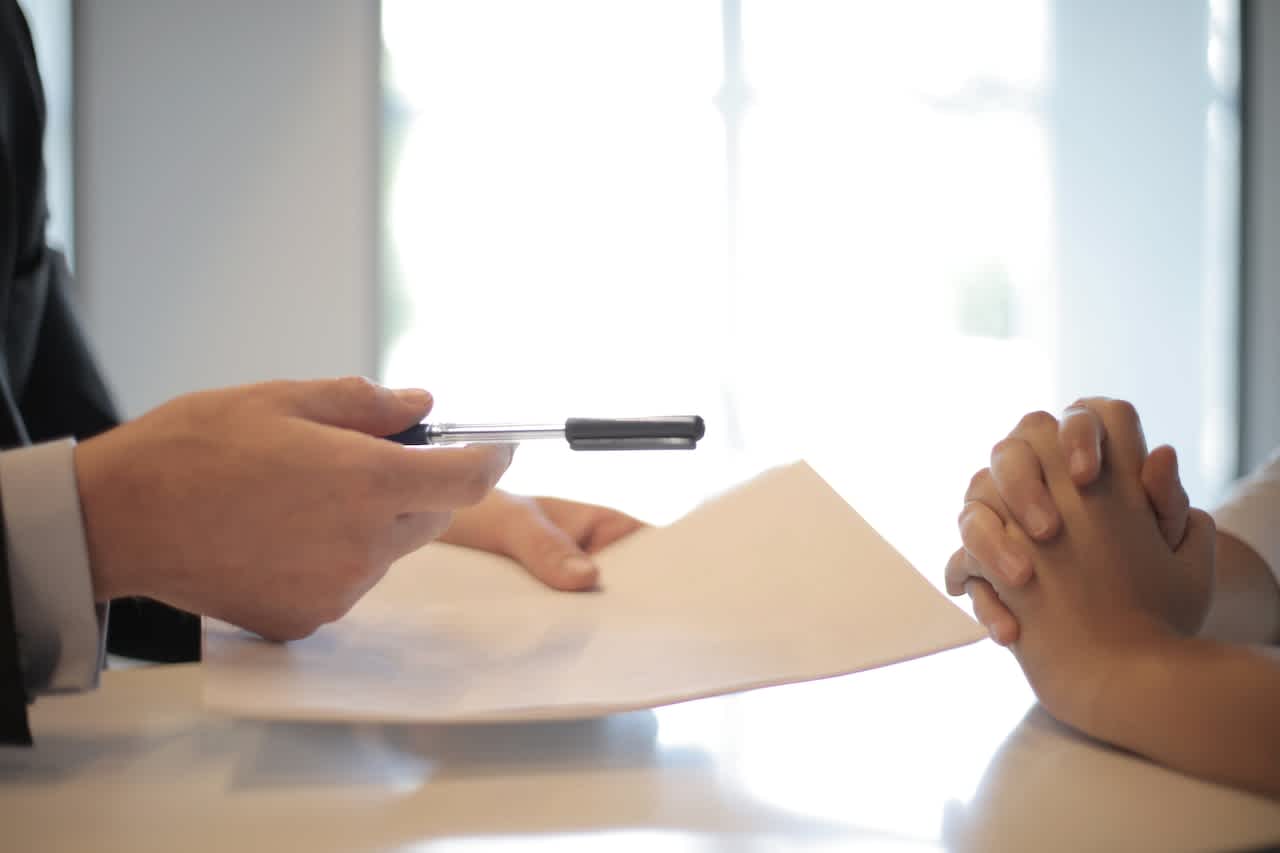 Person handing insurance coverage document for other person to sign