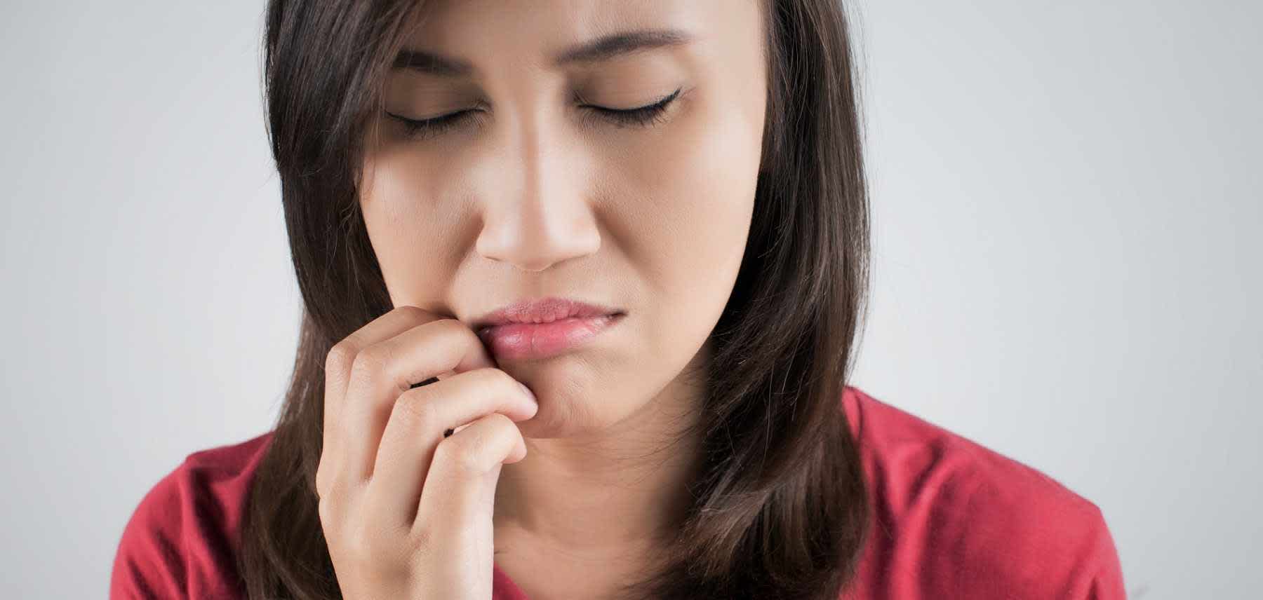 Young woman with painful sore wondering what causes mouth sores