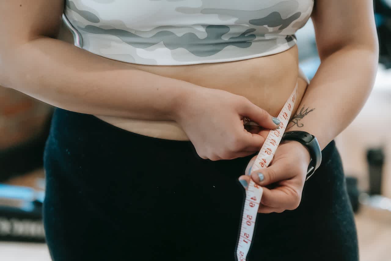 Woman measuring waistline while wondering how quickly Ozempic® works