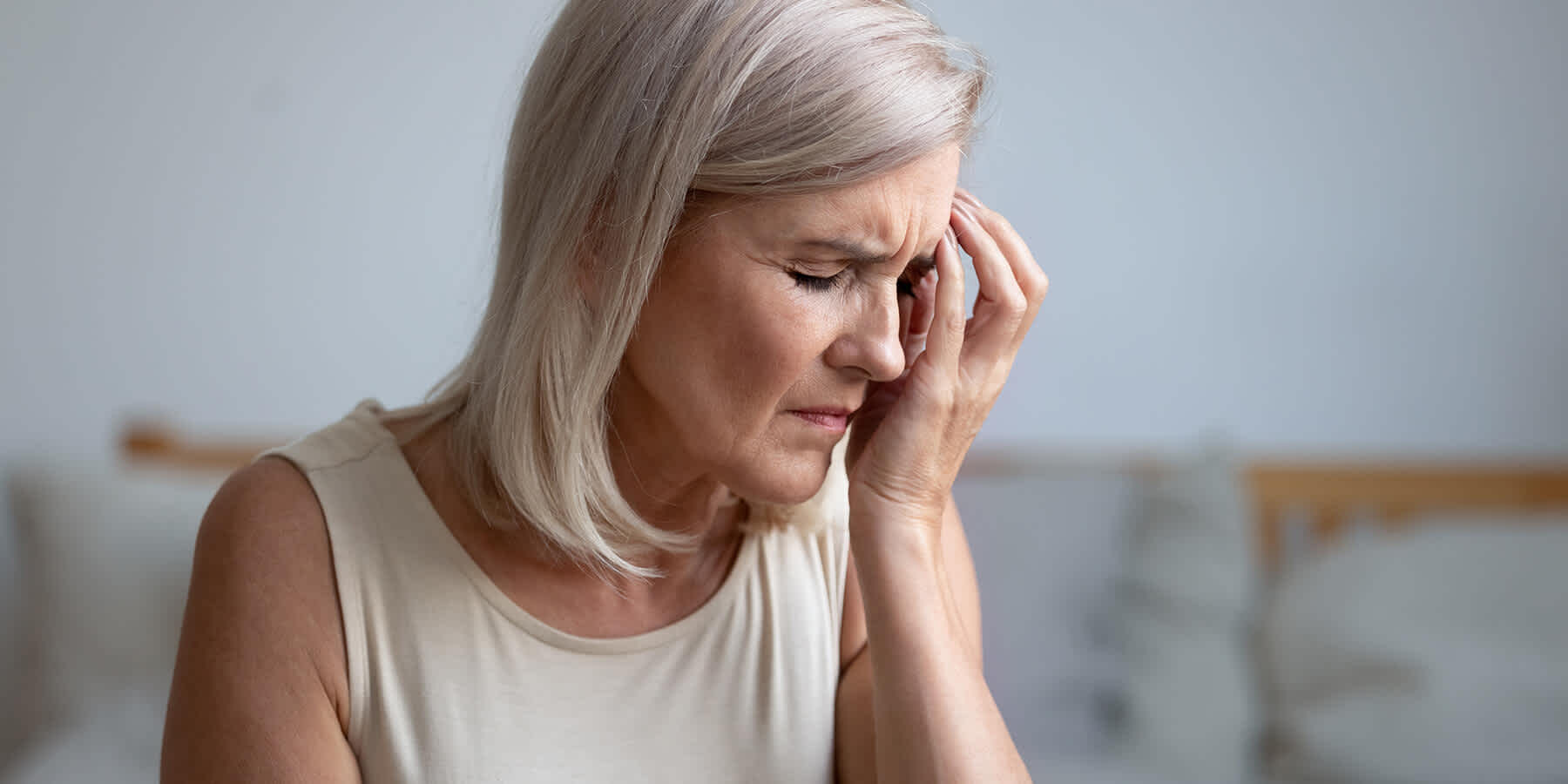 Woman with face in hand experiencing common symptom of postmenopause