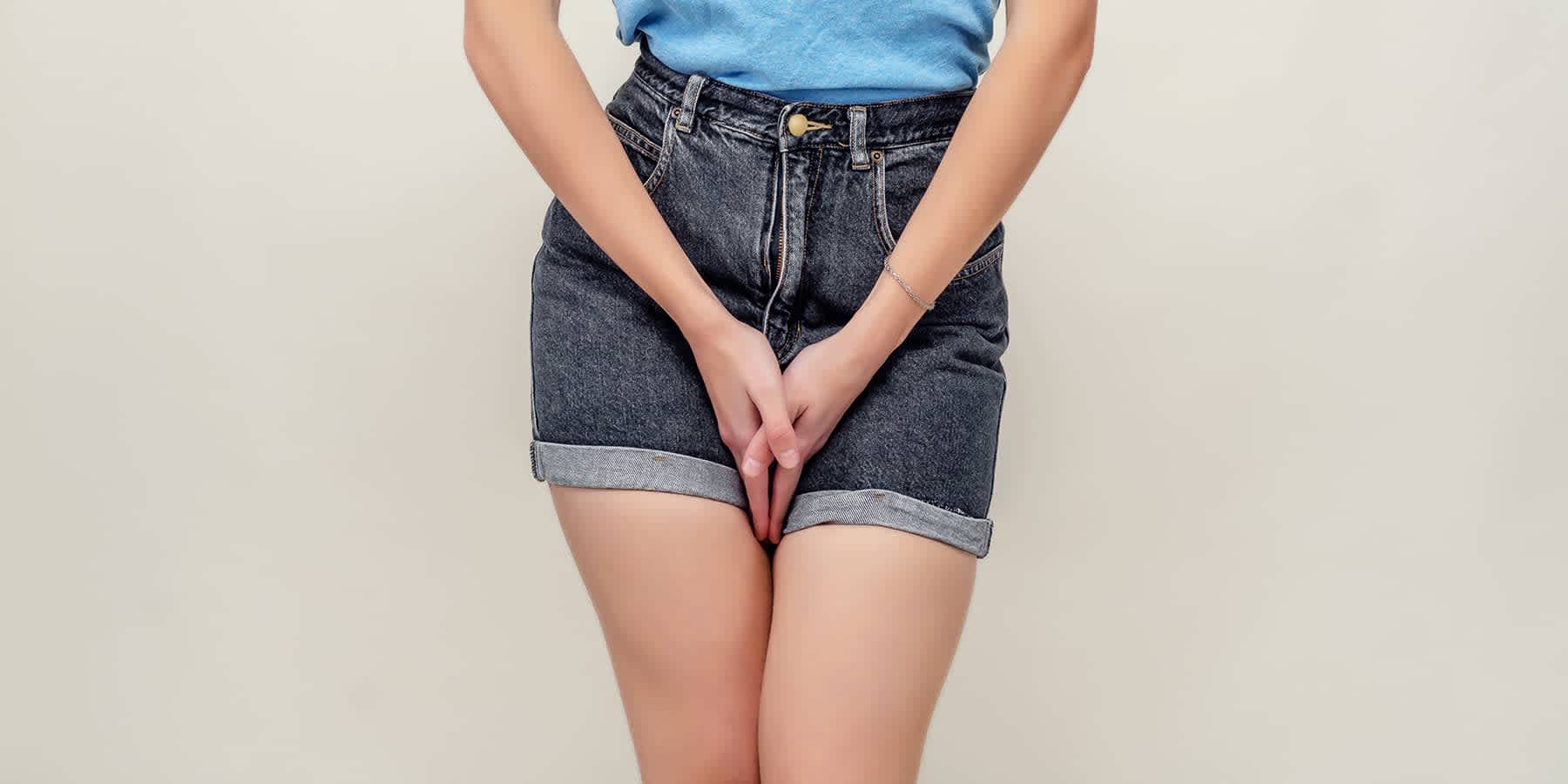 Woman in shorts with hands over groin wondering if a yeast infection can cause bleeding