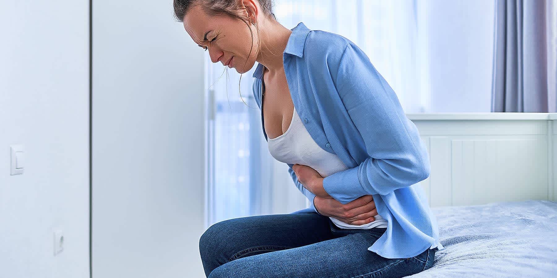 Woman with hands over her stomach experiencing discomfort after eating foods that cause gas