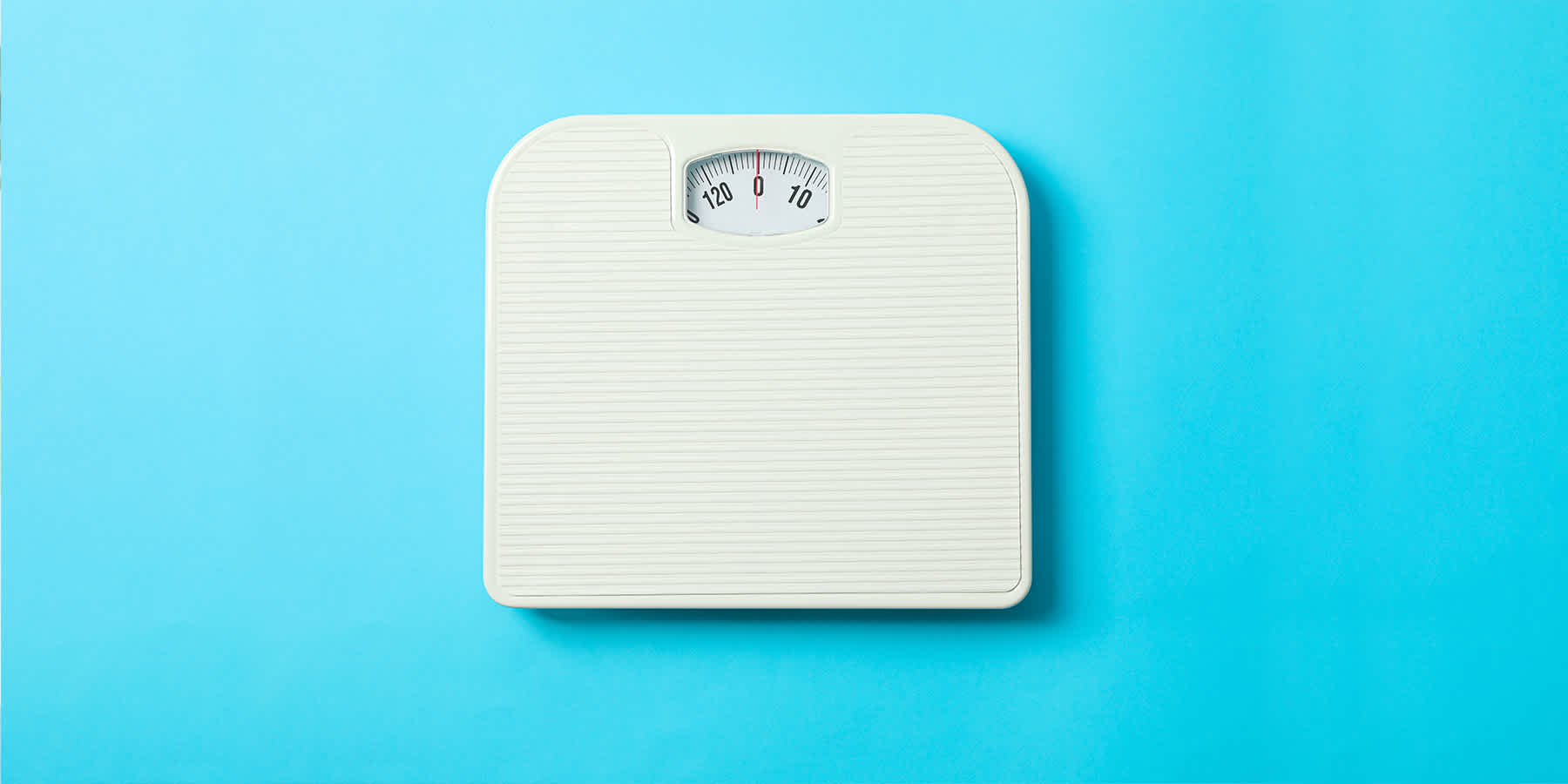 Bathroom scale against blue background that can be used to check weight gain with PCOS